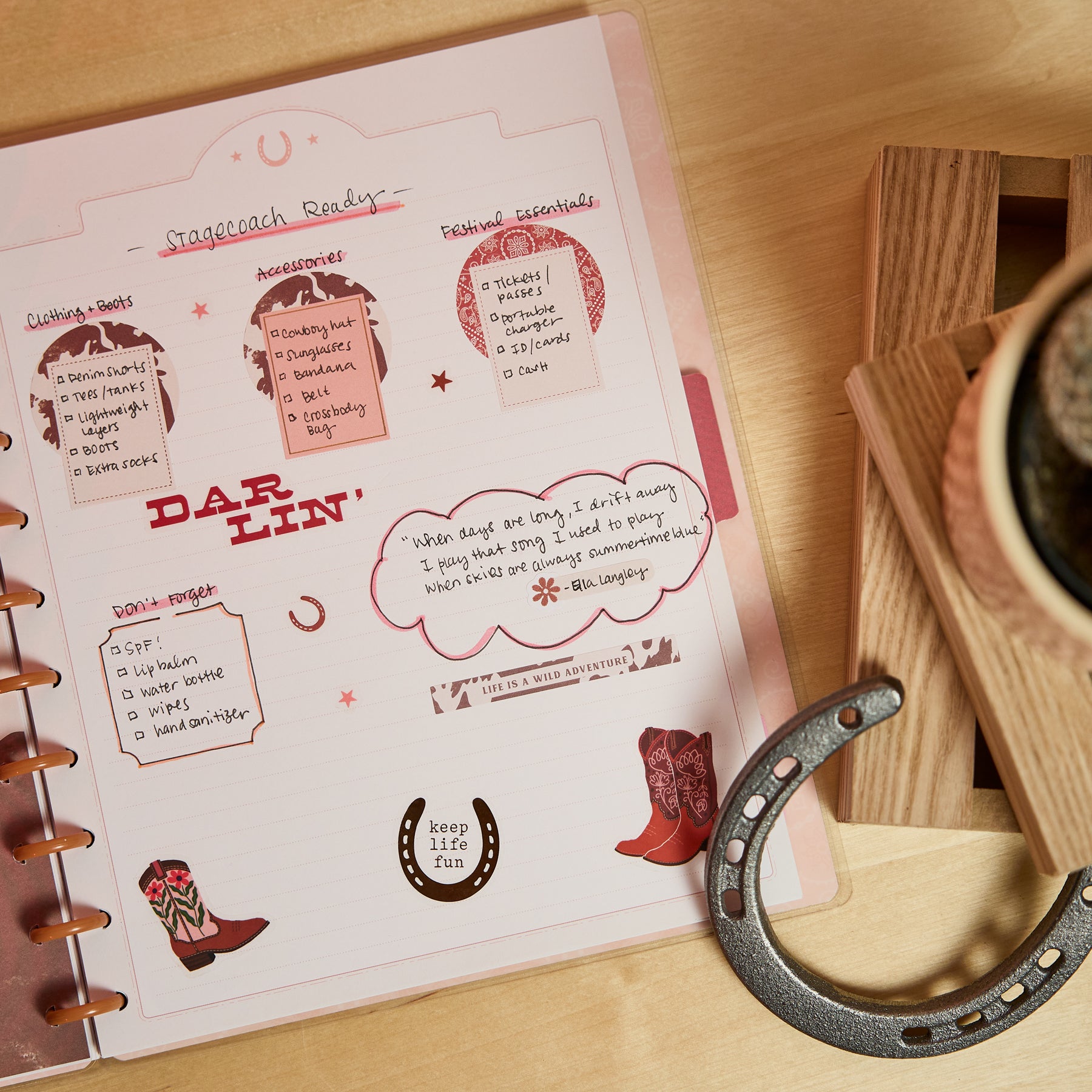 Page from the Western Bloom - Dotted Lined Big Notebook - 60 Sheets featuring a handwritten stagecoach readiness checklist with decorative cowboy boots, horseshoes, and western-themed accents on a dotted and lined page next to a wooden coaster and black cup.