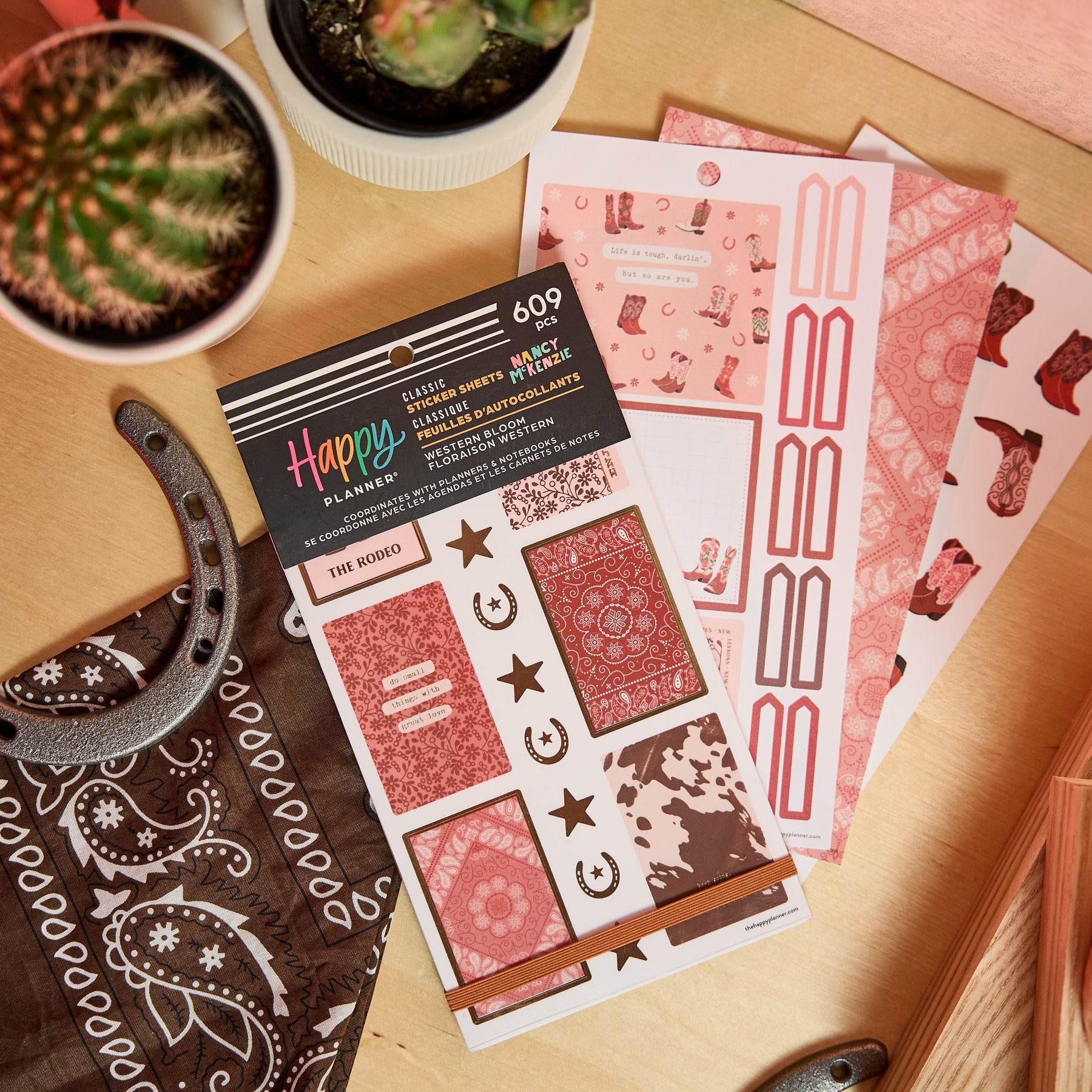 Western Bloom - Value Pack Stickers featuring Western-themed designs with cowgirl boots, bandanas, horseshoes, and florals, displayed on a wooden surface with cacti and horseshoe accents.