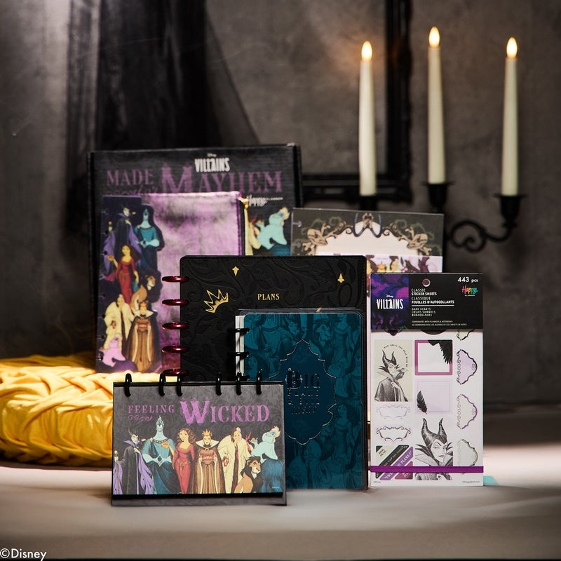 Collection of themed planners and accessories on a surface with candles in the background